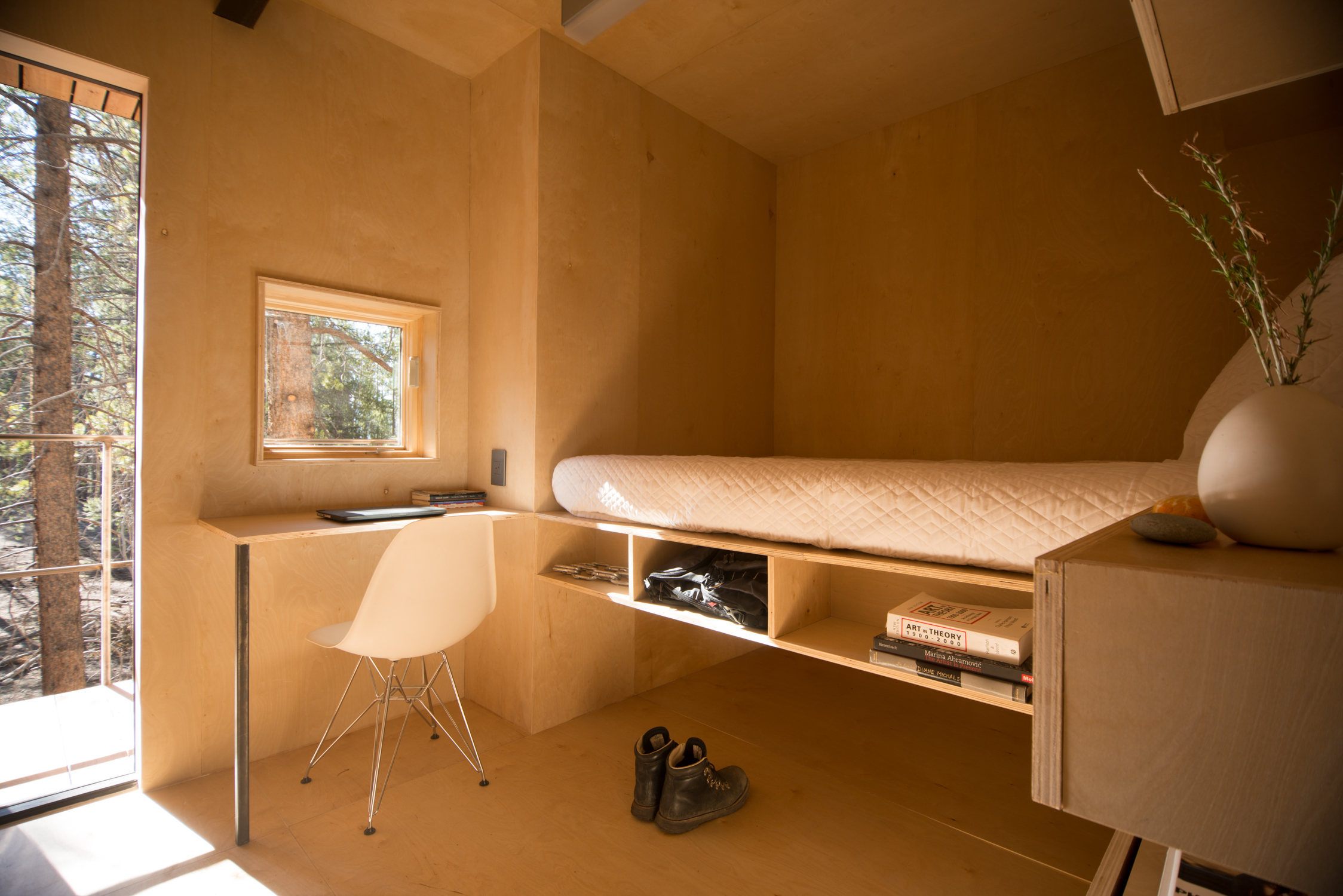 Mountain Modern Cabins — interior, tall narrow window framing lodgepole pine, birch plywood sleeping platform, Colorado Outward Bound School