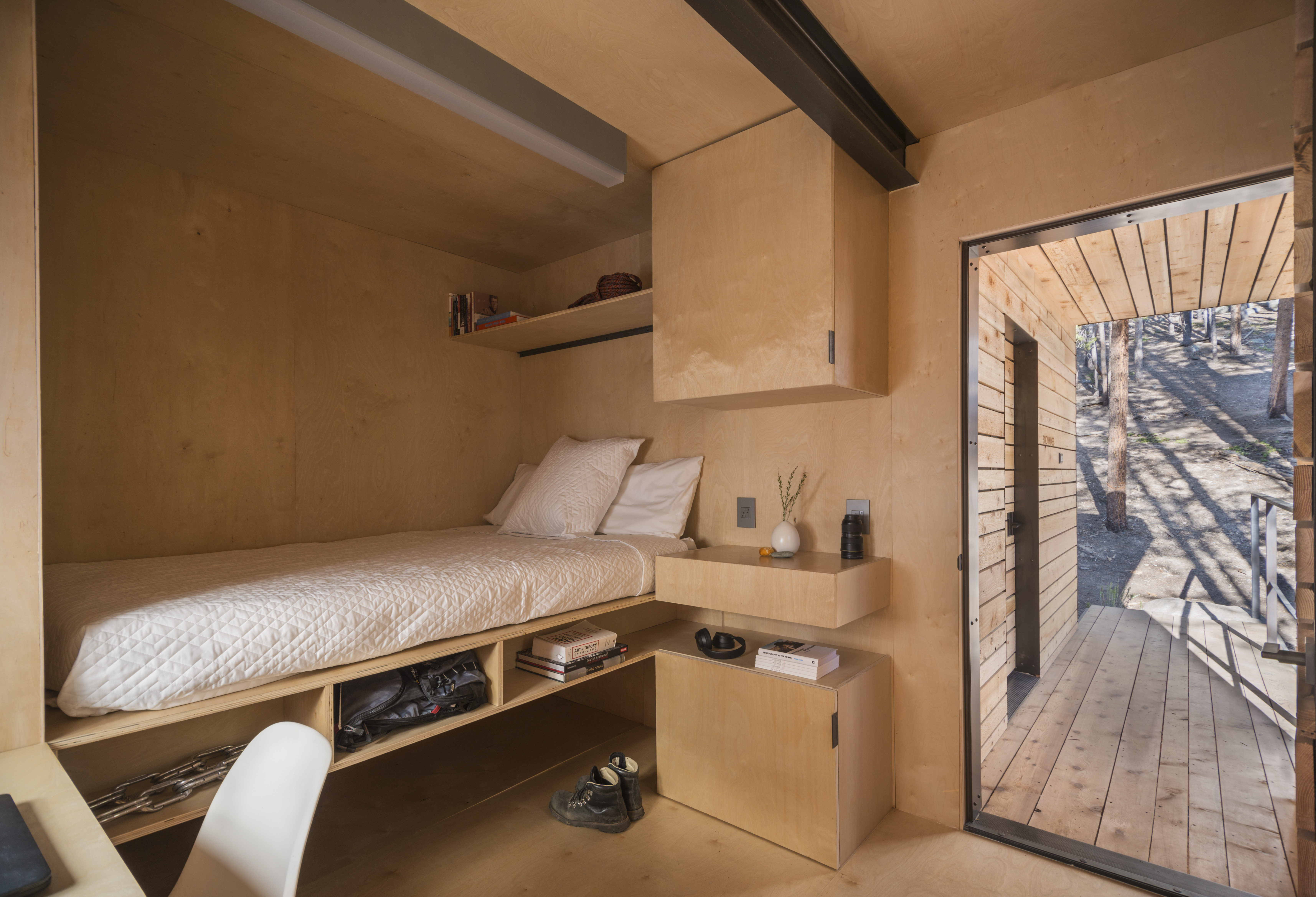 Mountain Modern Cabins — interior storage wall closed, full birch plywood panel, desk and workspace beside floor-to-ceiling window