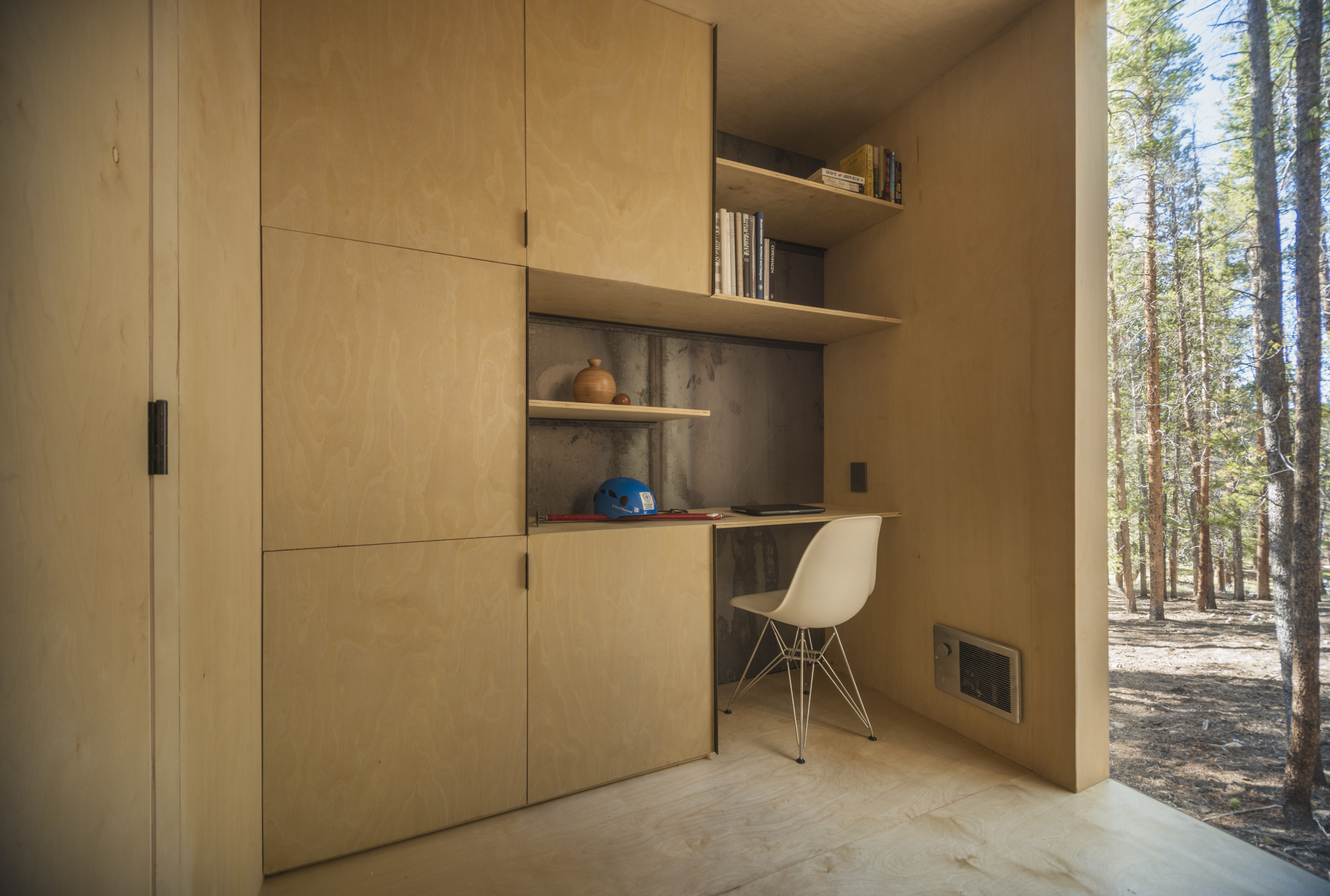 Mountain Modern Cabins — cedar porch door open, interior depth visible, birch plywood walls, exposed steel moment frame beam overhead