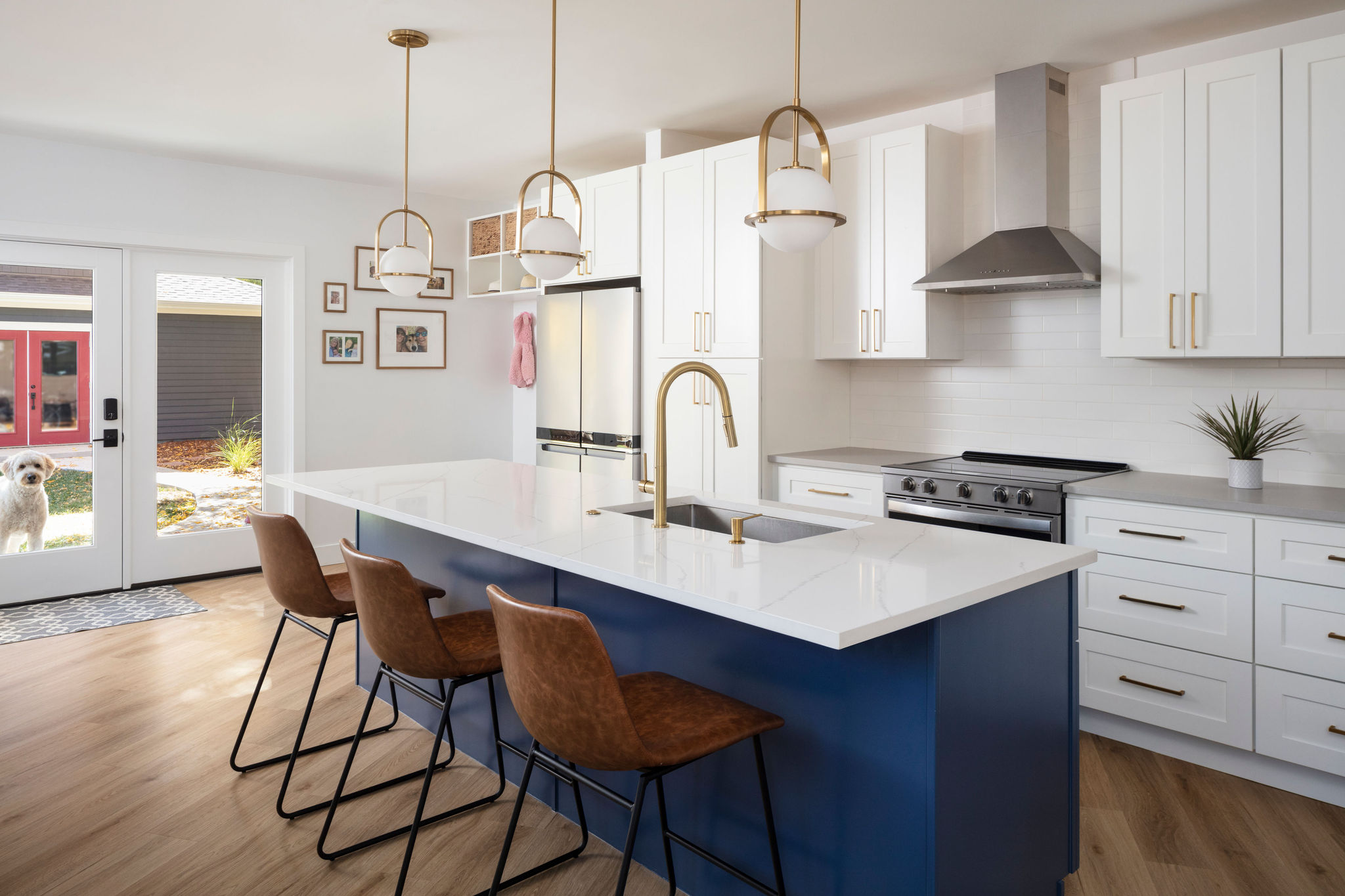 Open kitchen renovation in a Lafayette, Colorado home designed by Intentional Architecture, with blue island, brass pendants, and connection to the yard.